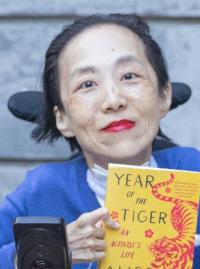 Alice Wong holds a copy of her memoir, Year of the Tiger: An Activist's Life.